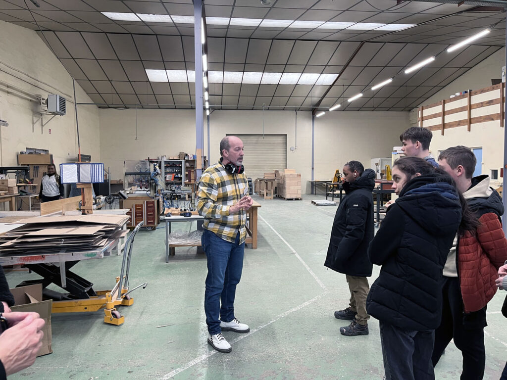 Responsable de l’atelier menuiserie de PROMUT détaillant aux jeunes visiteurs les différentes étapes de transformation du bois.